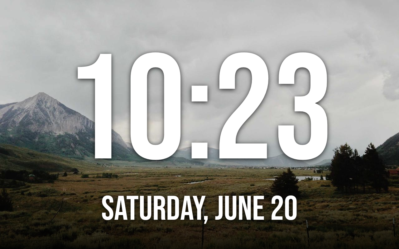 The photo-frame screensaver showing a large clock over a landscape photo